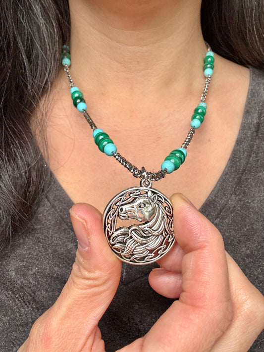 Necklace with a horse pendant held by a person