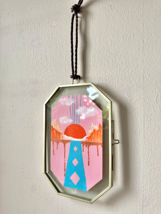 Small abstract landscape painting in a glass frame hanging against a white wall