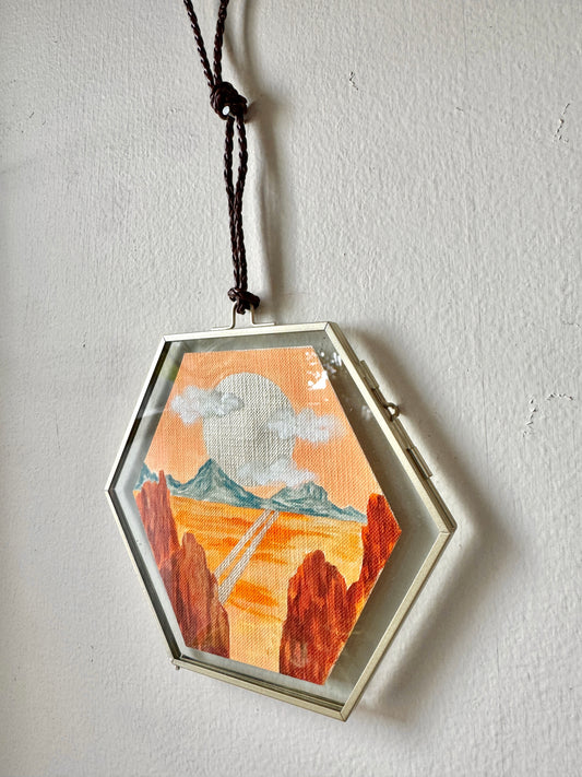 Glass framed landscape painting hanging on a white wall