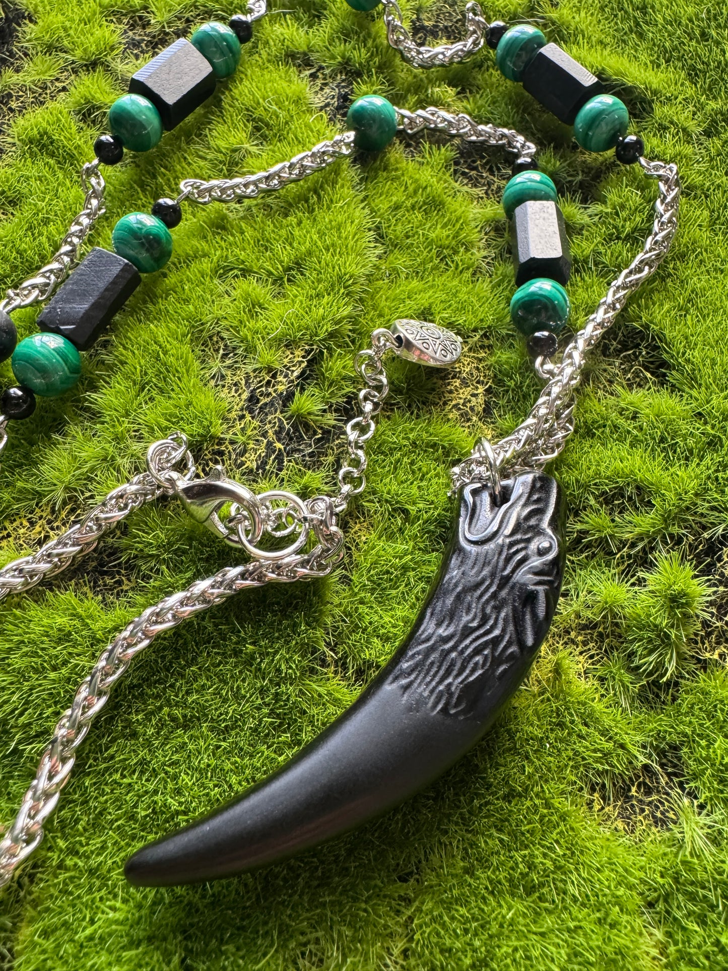 Necklace with a large claw pendant on a grassy background