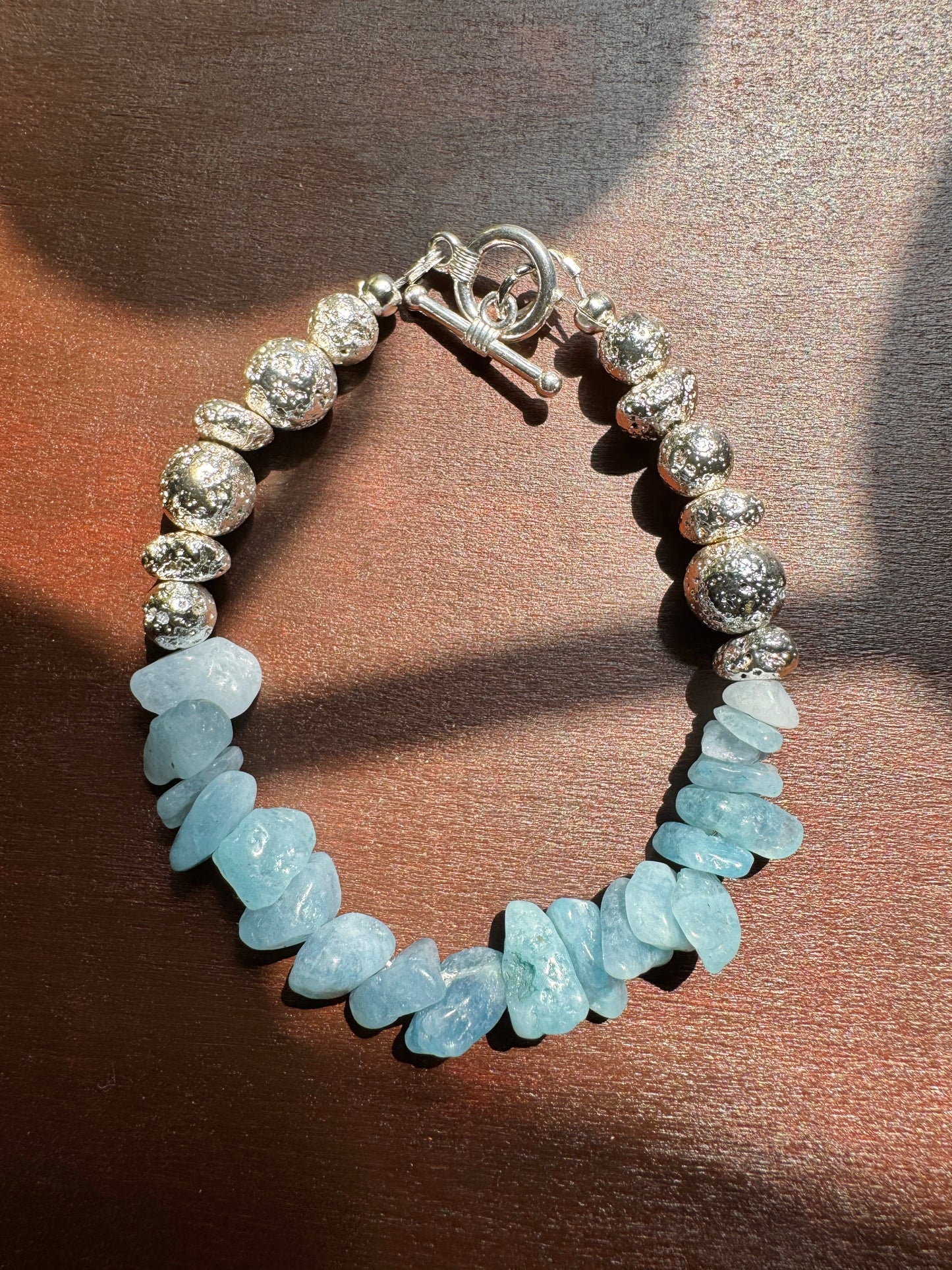 Bracelet with silver beads and light blue stone beads on a brown background