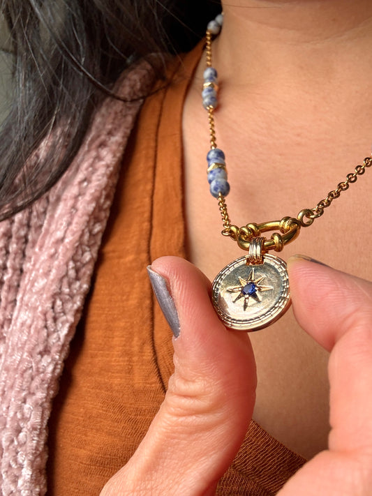 Close up of blue stone in gold plated pendant on stainless steel gold plated chain with sodalite beads