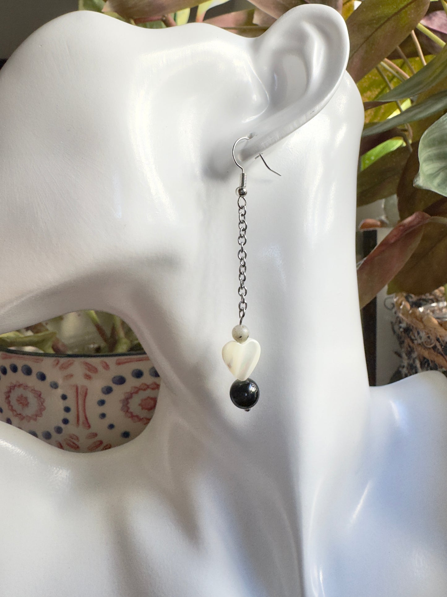 Earring with beads on a mannequin ear against a blurred background