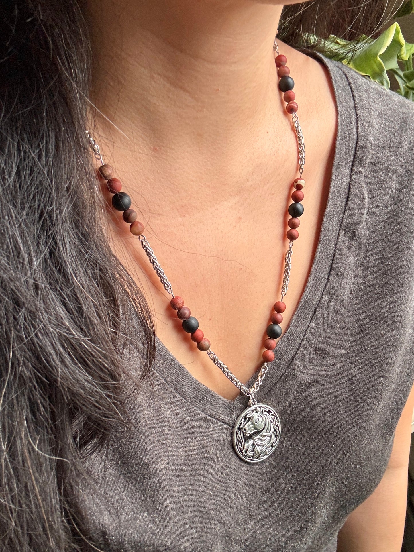Necklace with a horse pendant worn by a person, focusing on the necklace and its details.