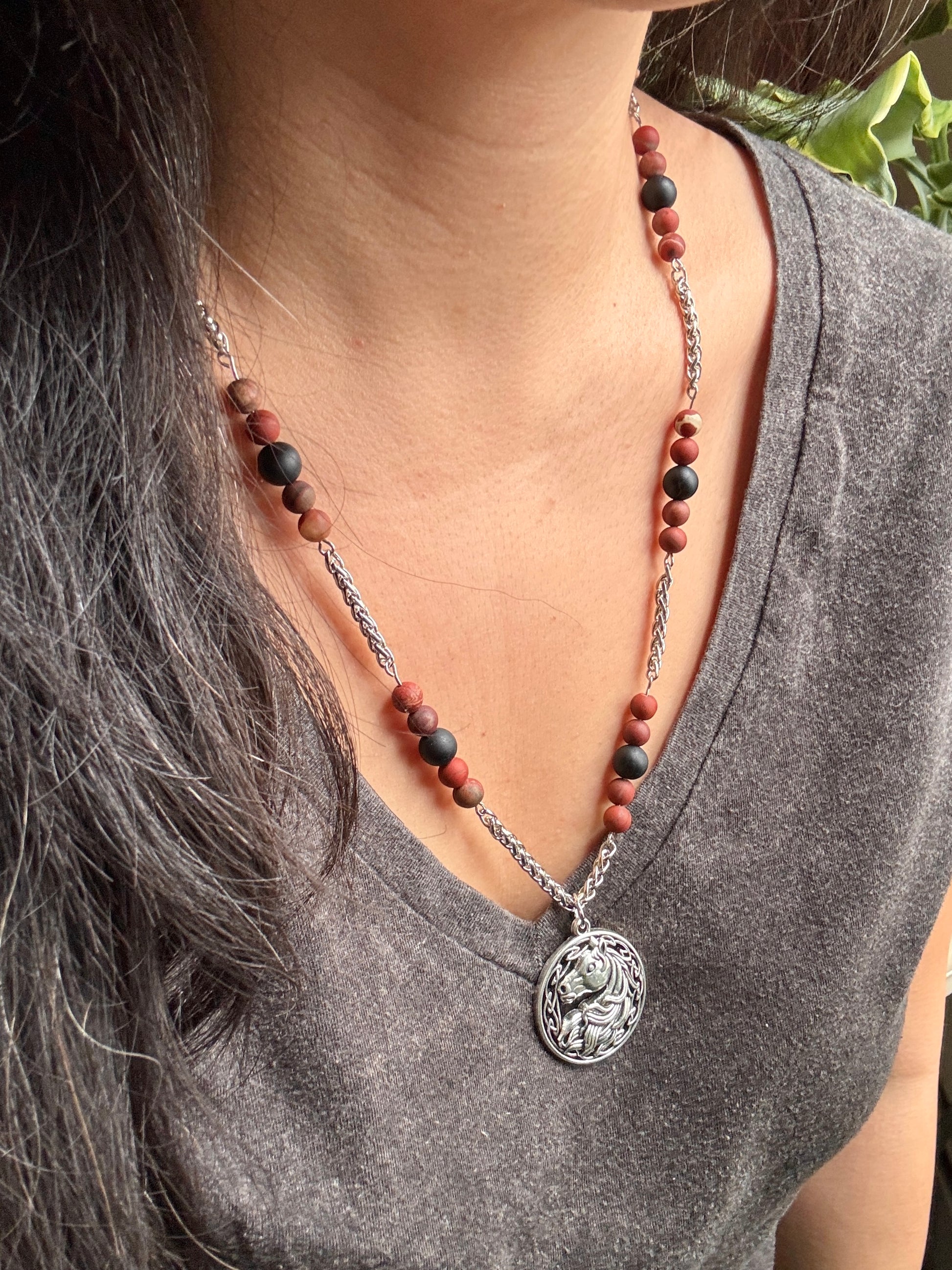 Necklace with a horse pendant worn by a person, focusing on the necklace and its details.