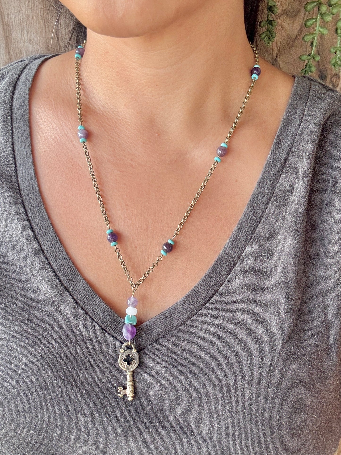 Necklace with a key pendant worn by a person in a gray shirt