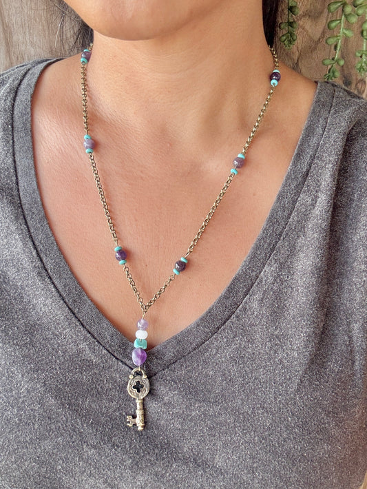 Necklace with a key pendant worn by a person in a gray shirt