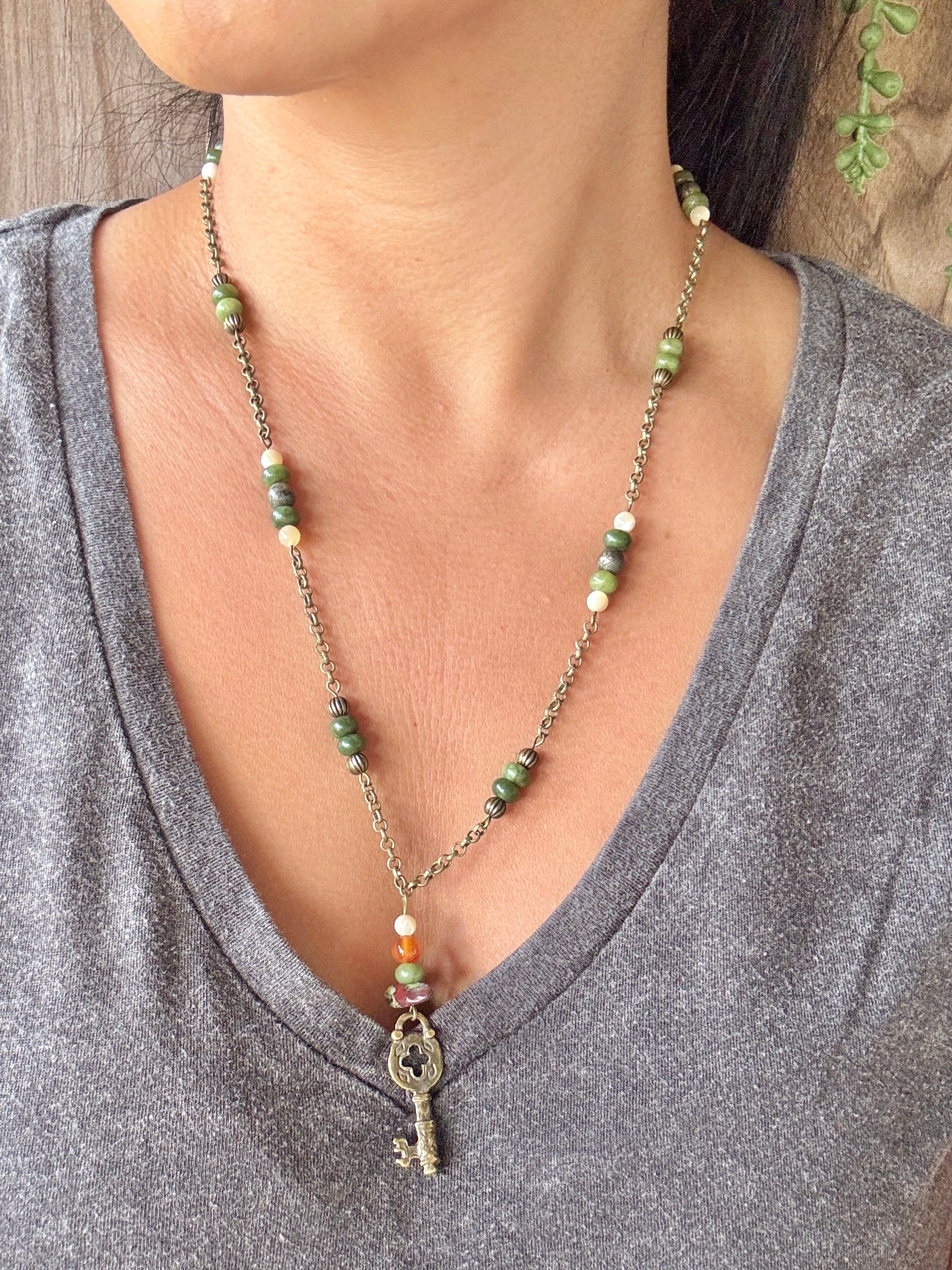 Necklace with a key pendant worn by a person in a gray shirt