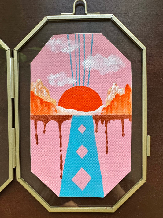 Geometric shape blue and pink landscape painting against a glass frame on a wood background
