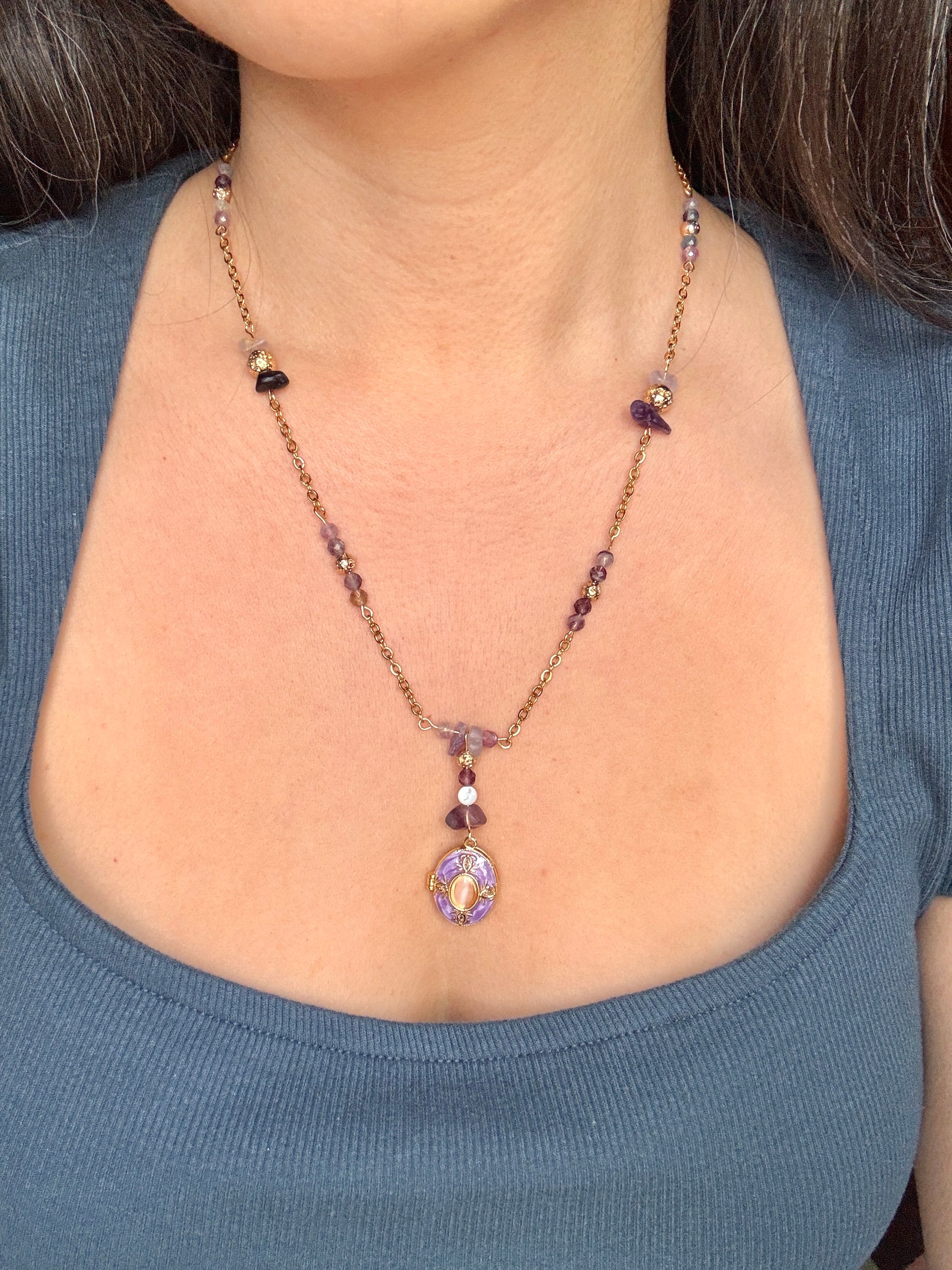 Necklace with a pendant worn by a person against a blue shirt background