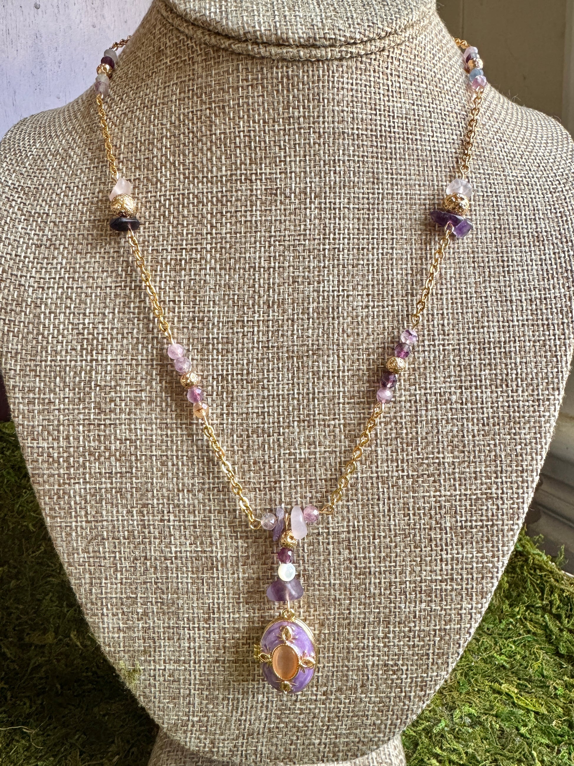 Necklace with purple and gold elements on a mannequin bust.