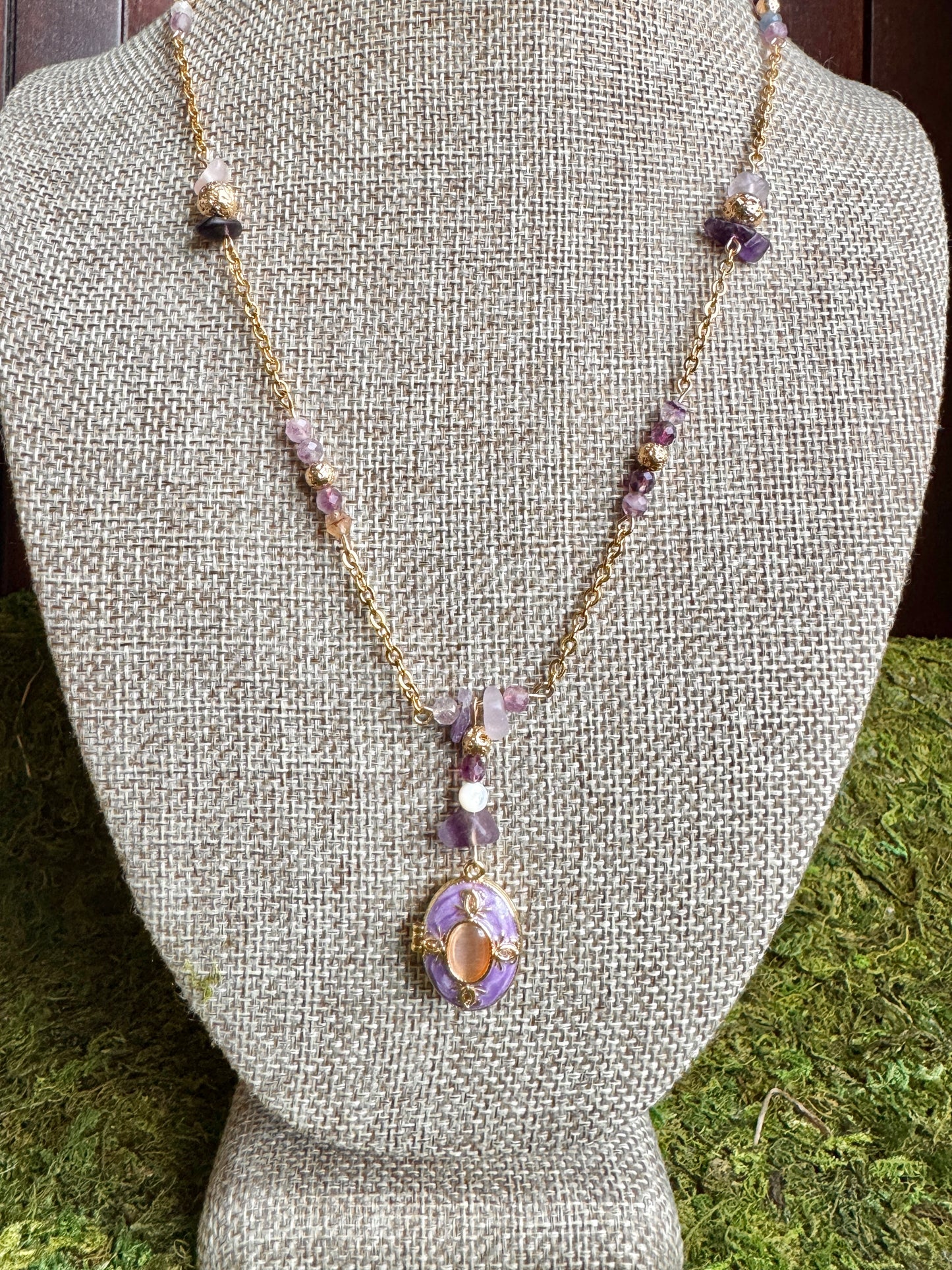 Necklace with a purple pendant on a gray bust against a green grass background