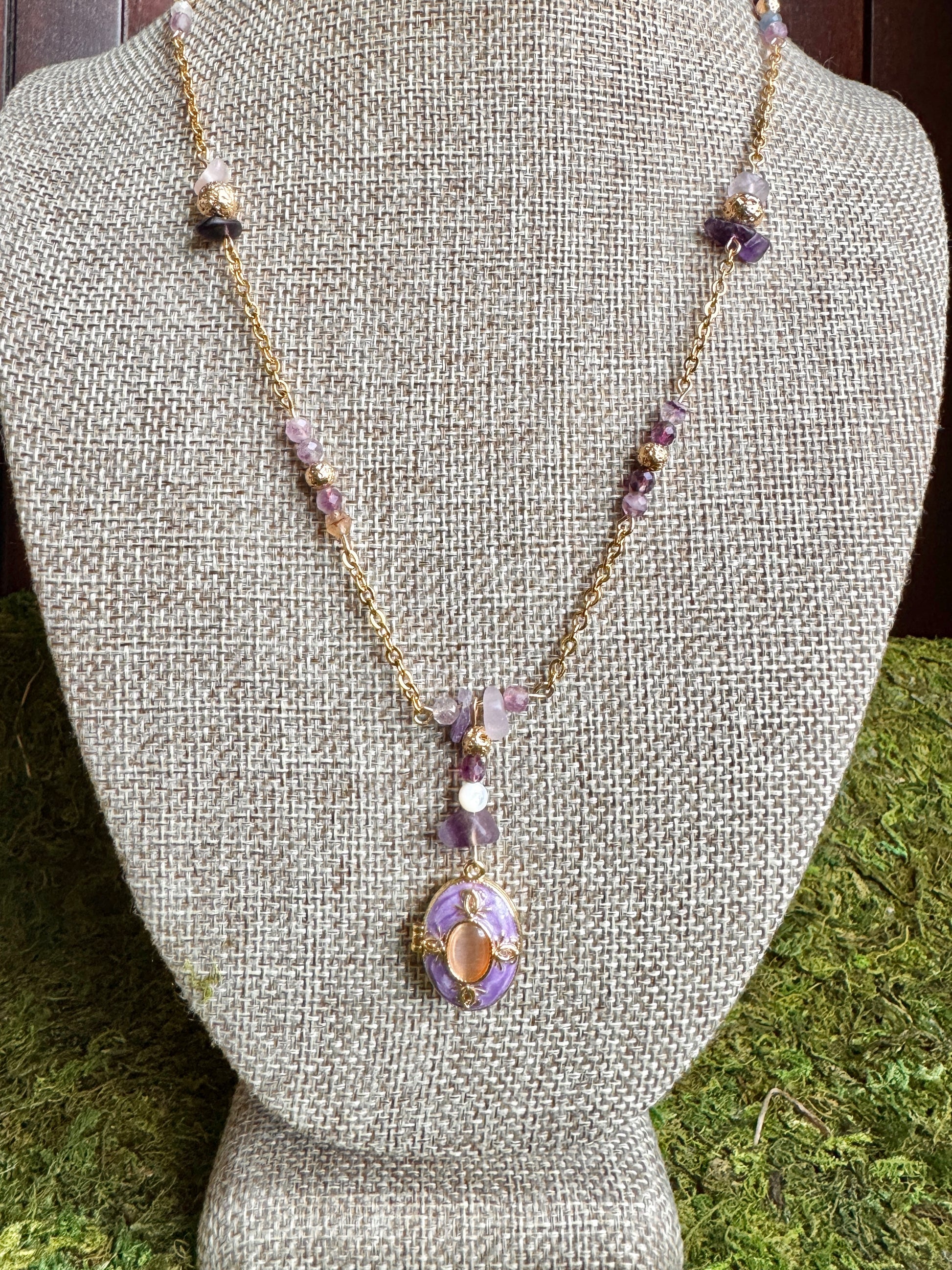 Necklace with a purple pendant on a gray bust against a green grass background