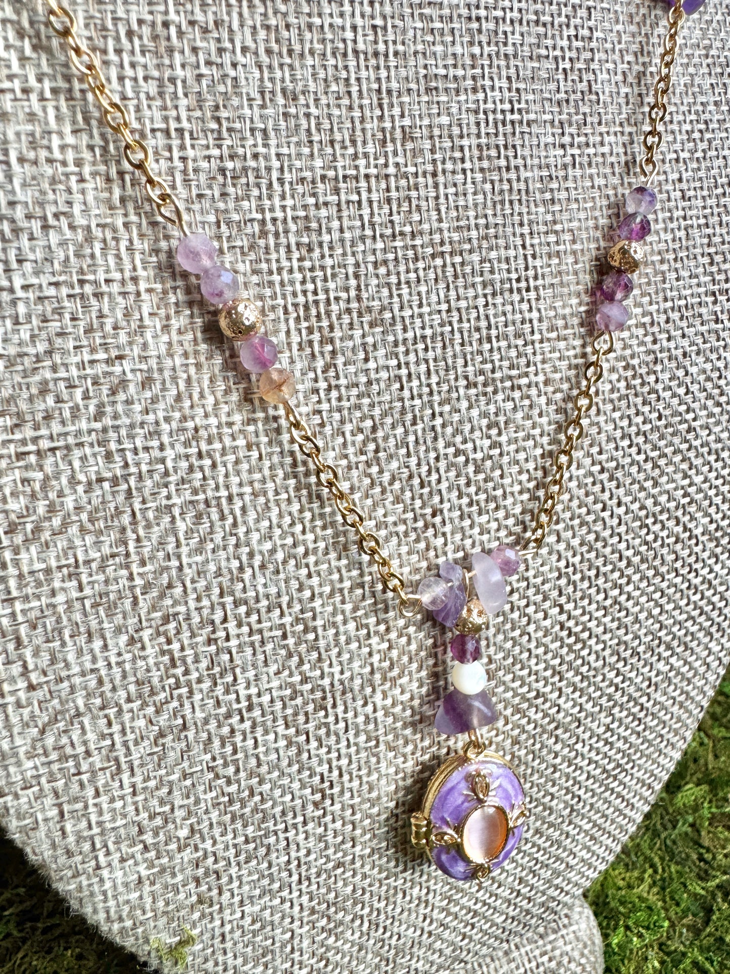 Necklace with purple beads and a pendant on a textured fabric background
