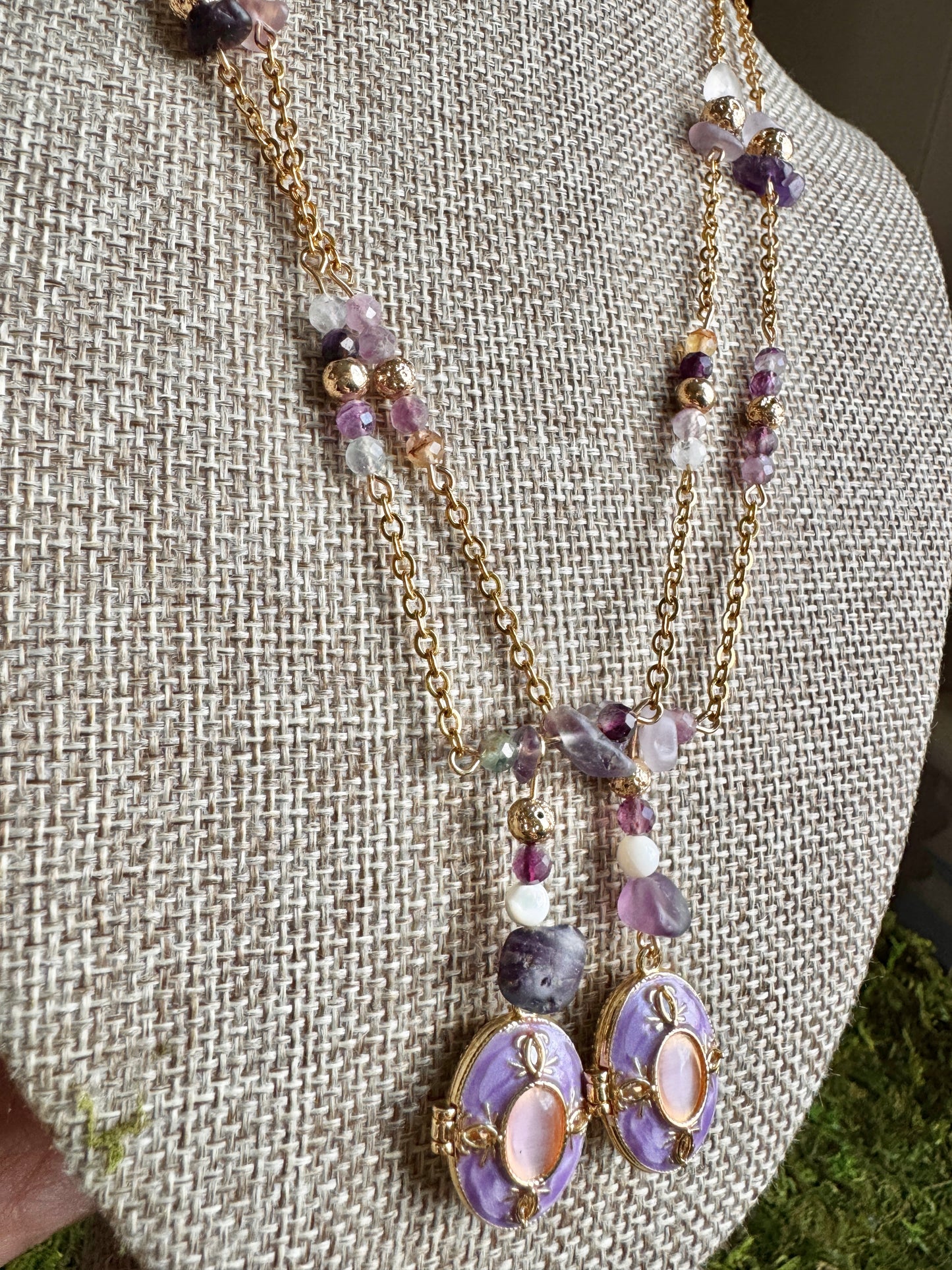 Necklace with purple and gold elements on a textured surface