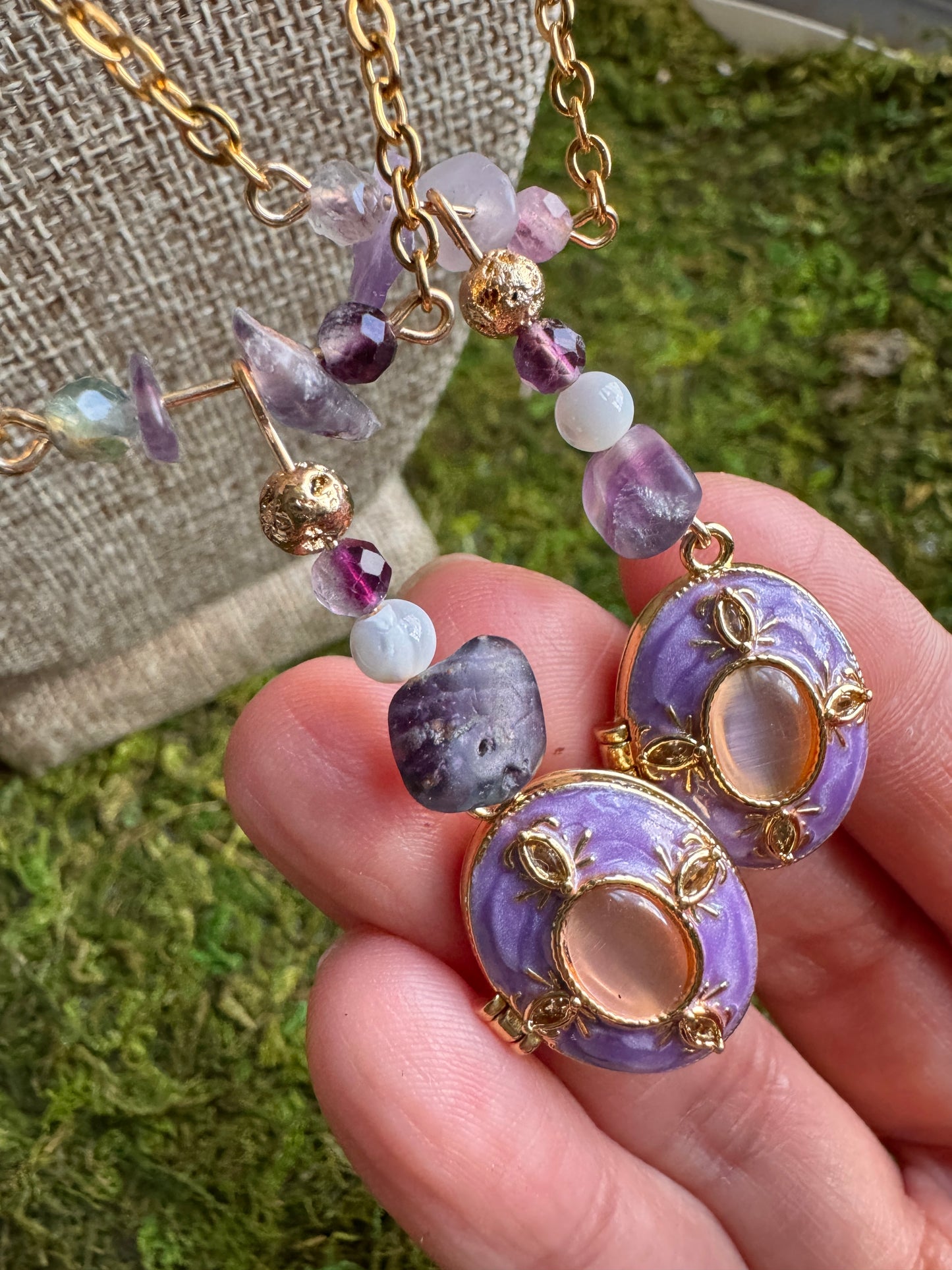 Purple beaded earrings held in a hand with a blurred background