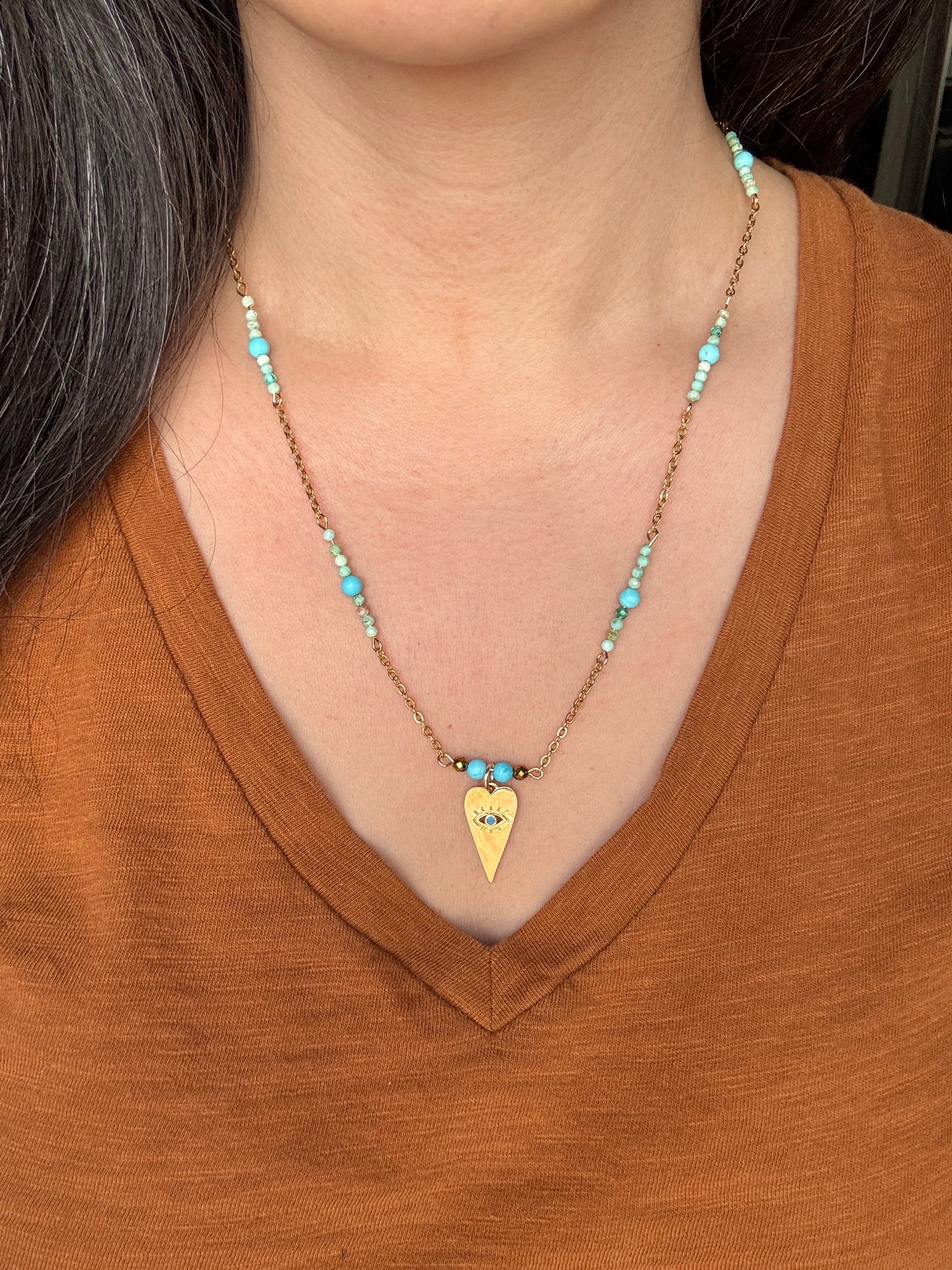 Necklace with a heart-shaped pendant worn by a person in a brown shirt