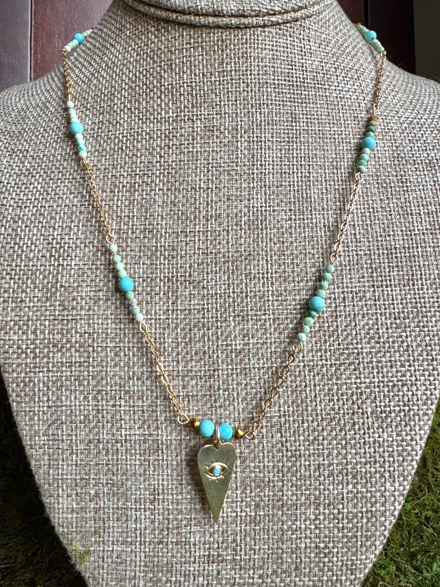 Necklace with turquoise beads and a heart-shaped pendant on a mannequin.