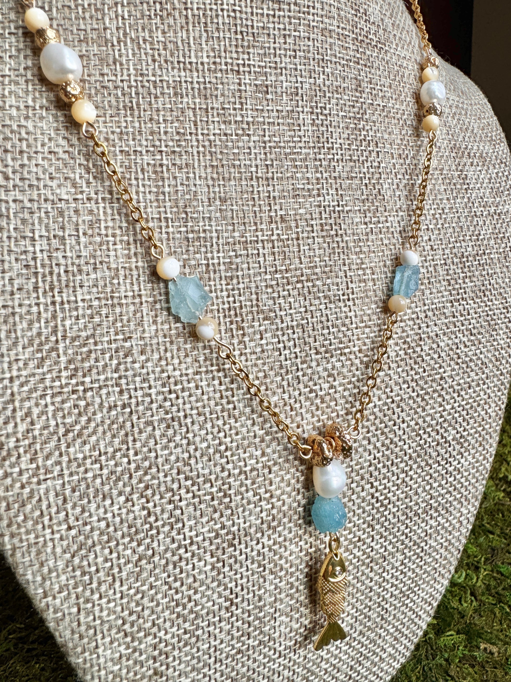 Necklace with pearls and blue beads on a textured surface