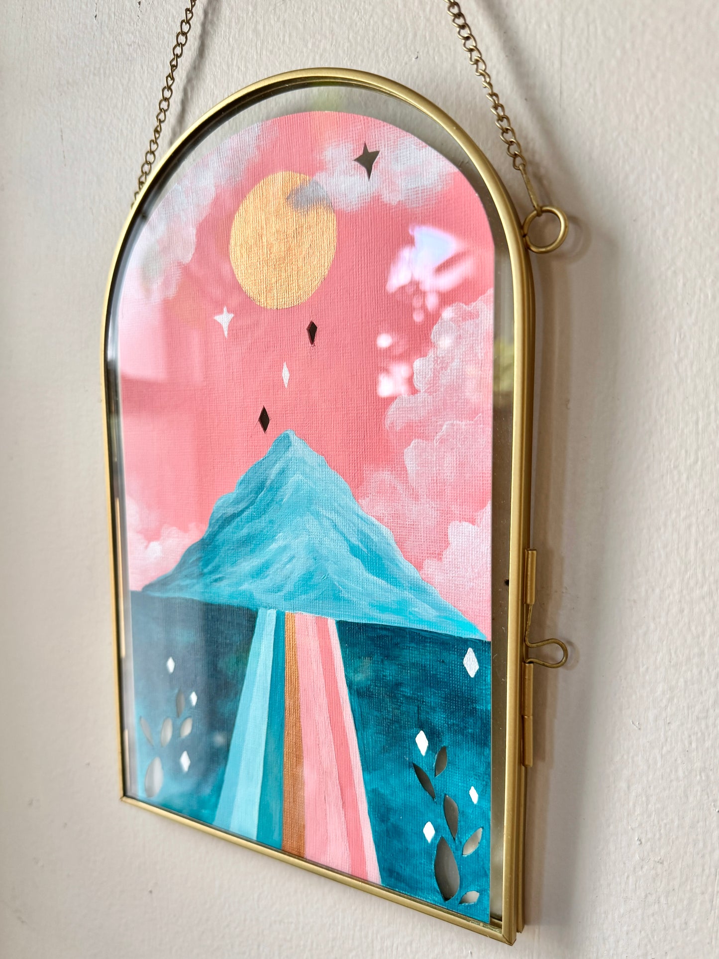 Landscape painting in glass frame hanging on white wall