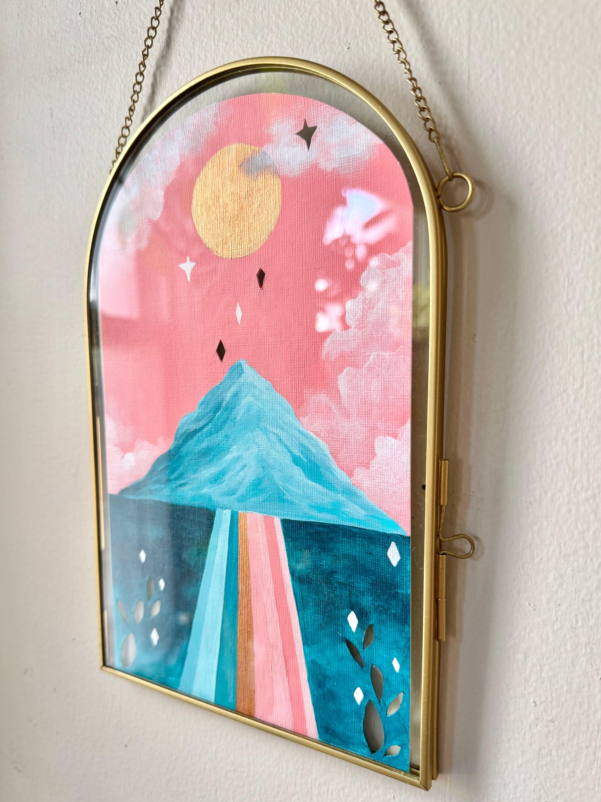 Landscape painting in glass frame hanging on white wall