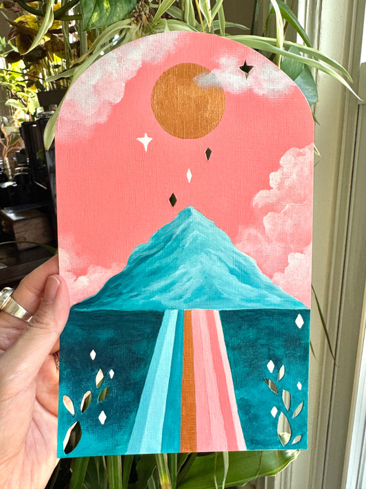 Painting on paper held up by a hand against a plant background