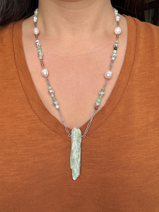 Necklace with a large pendant worn by a person in a brown shirt