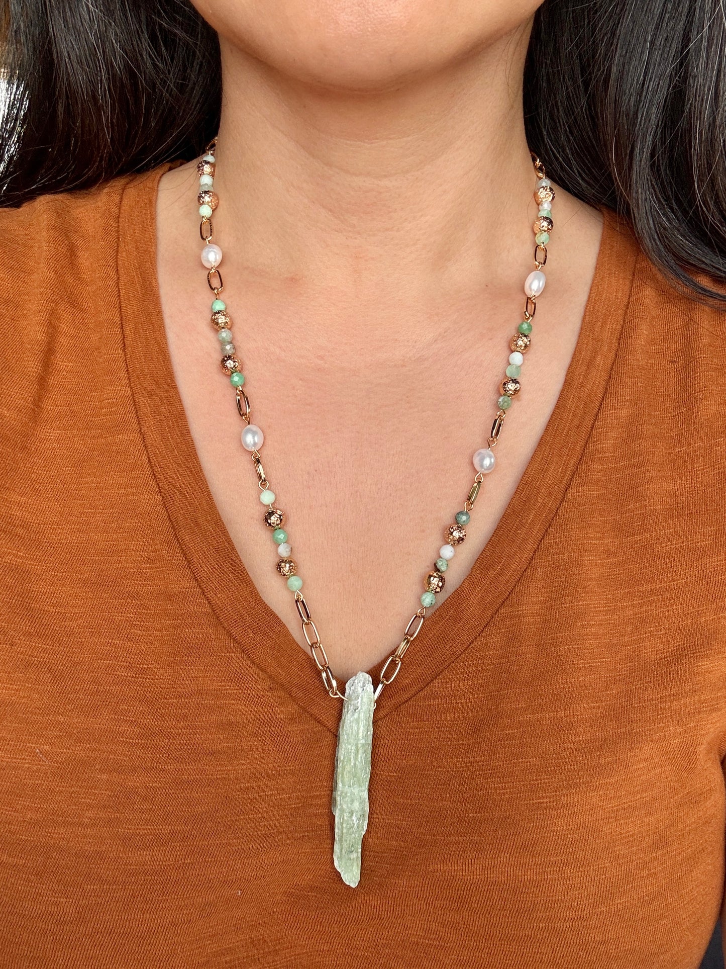 Necklace with a pendant worn by a person in a brown shirt