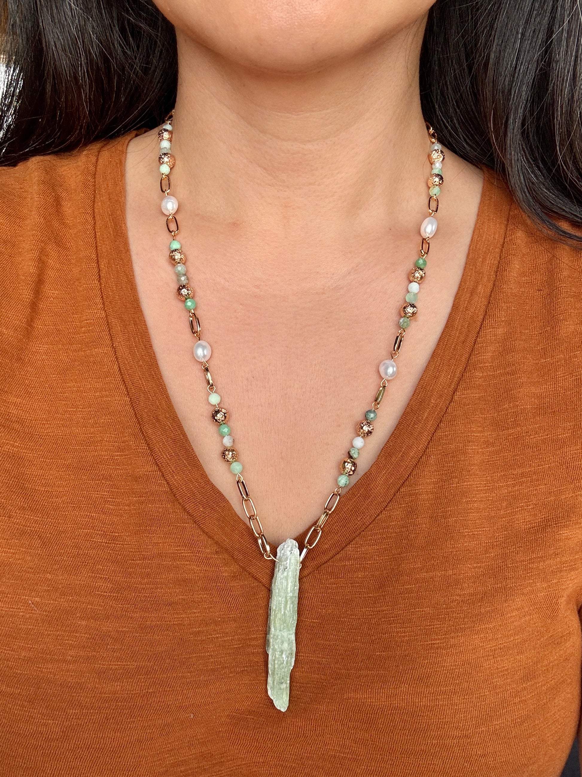 Necklace with a pendant worn by a person in a brown shirt