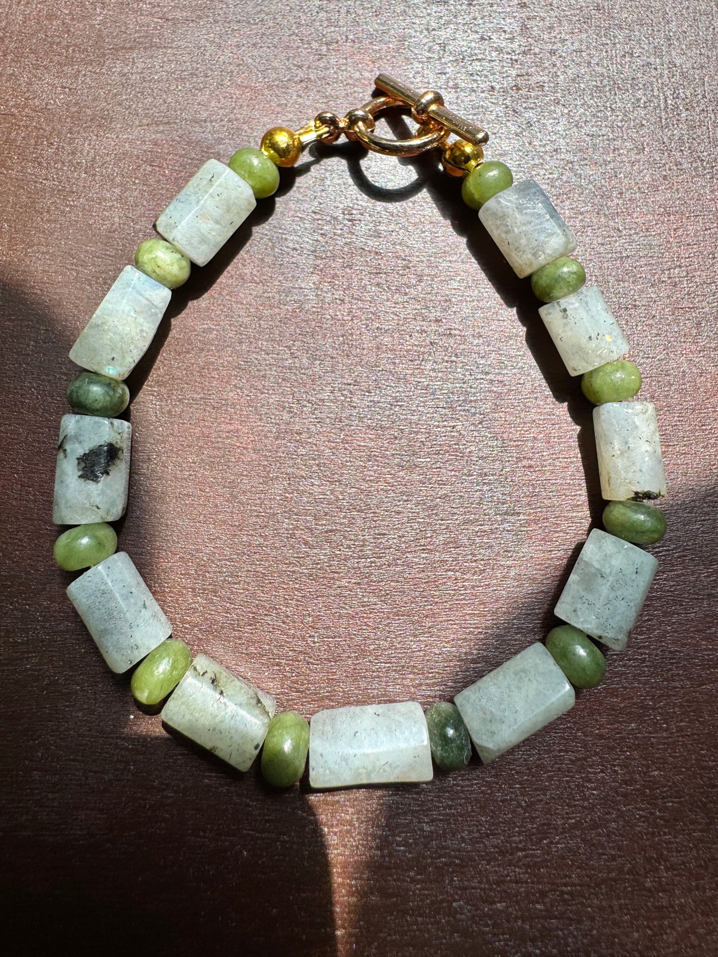 Bracelet with green and white beads on a wooden surface