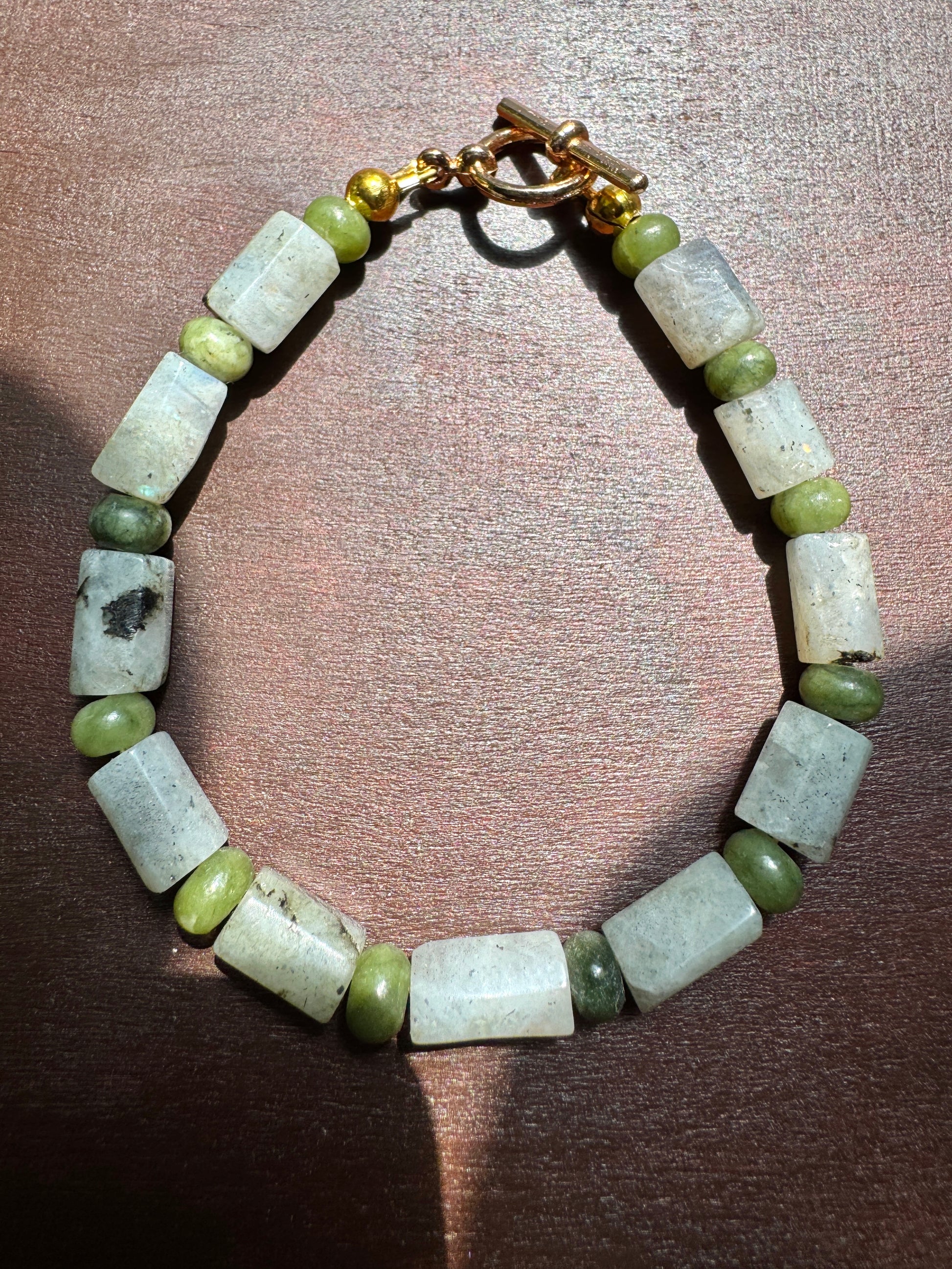 Bracelet with green and white beads on a wooden surface