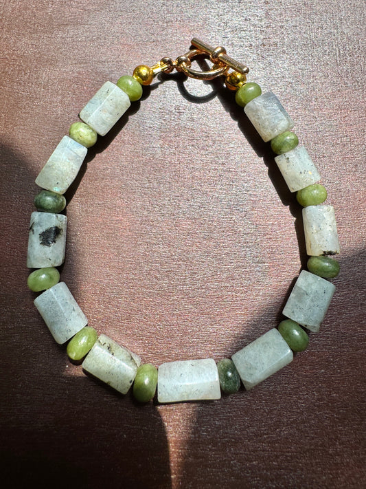 Bracelet with green and white beads on a wooden surface