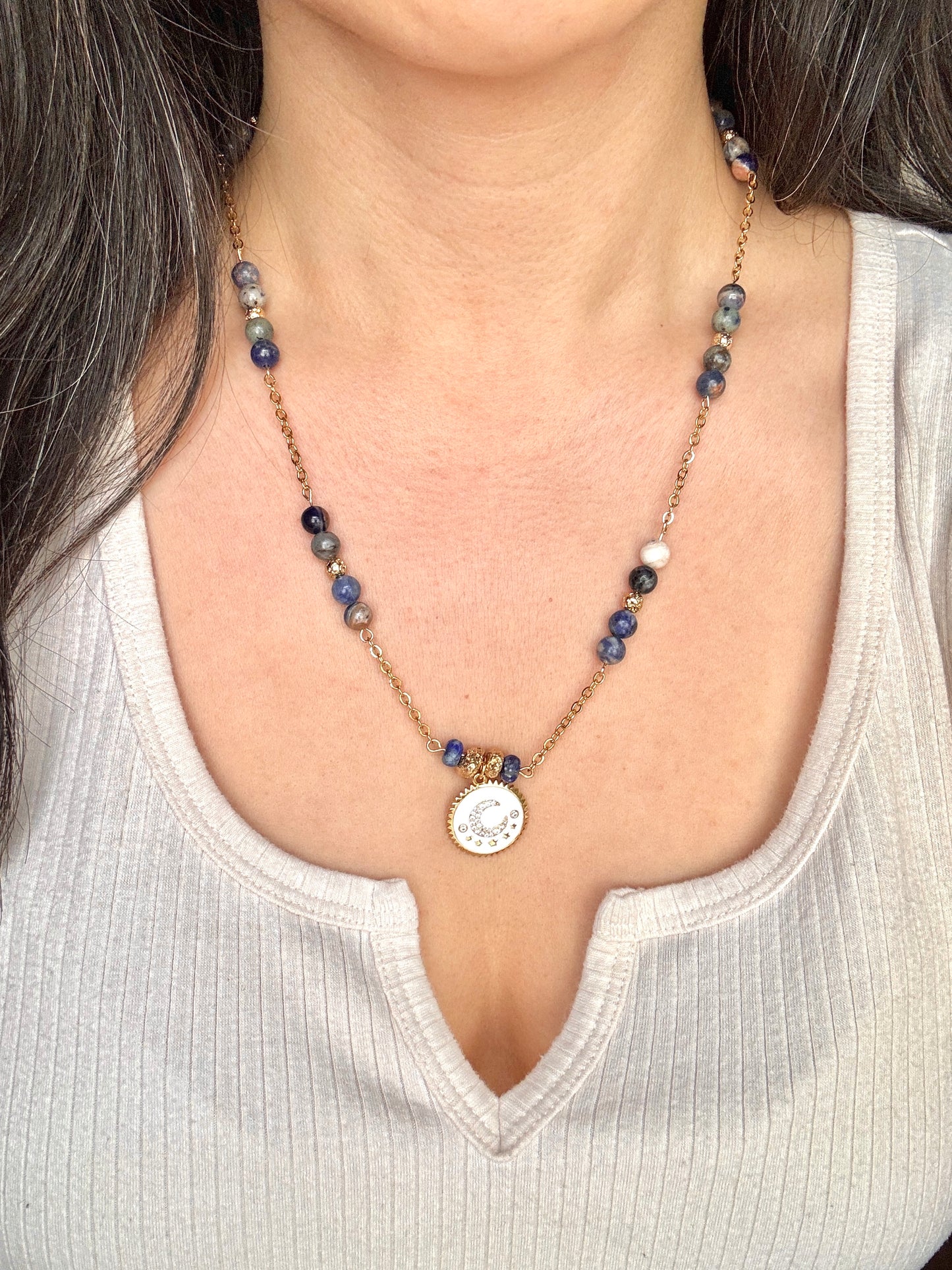 Necklace with a pendant worn by a person against a neutral background