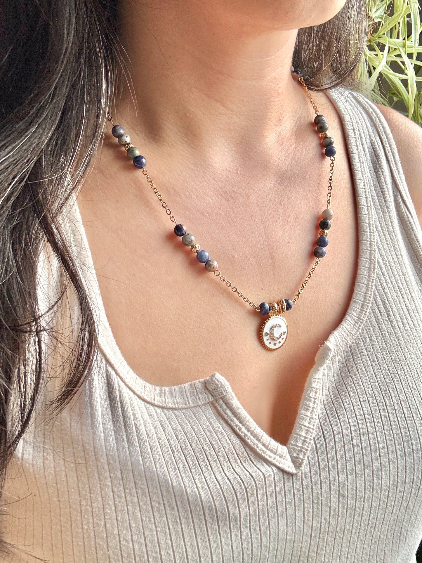 Necklace with a pendant worn by a person, with a neutral background