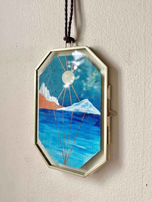 Geometric landscape painting in a glass frame hanging against a white wall
