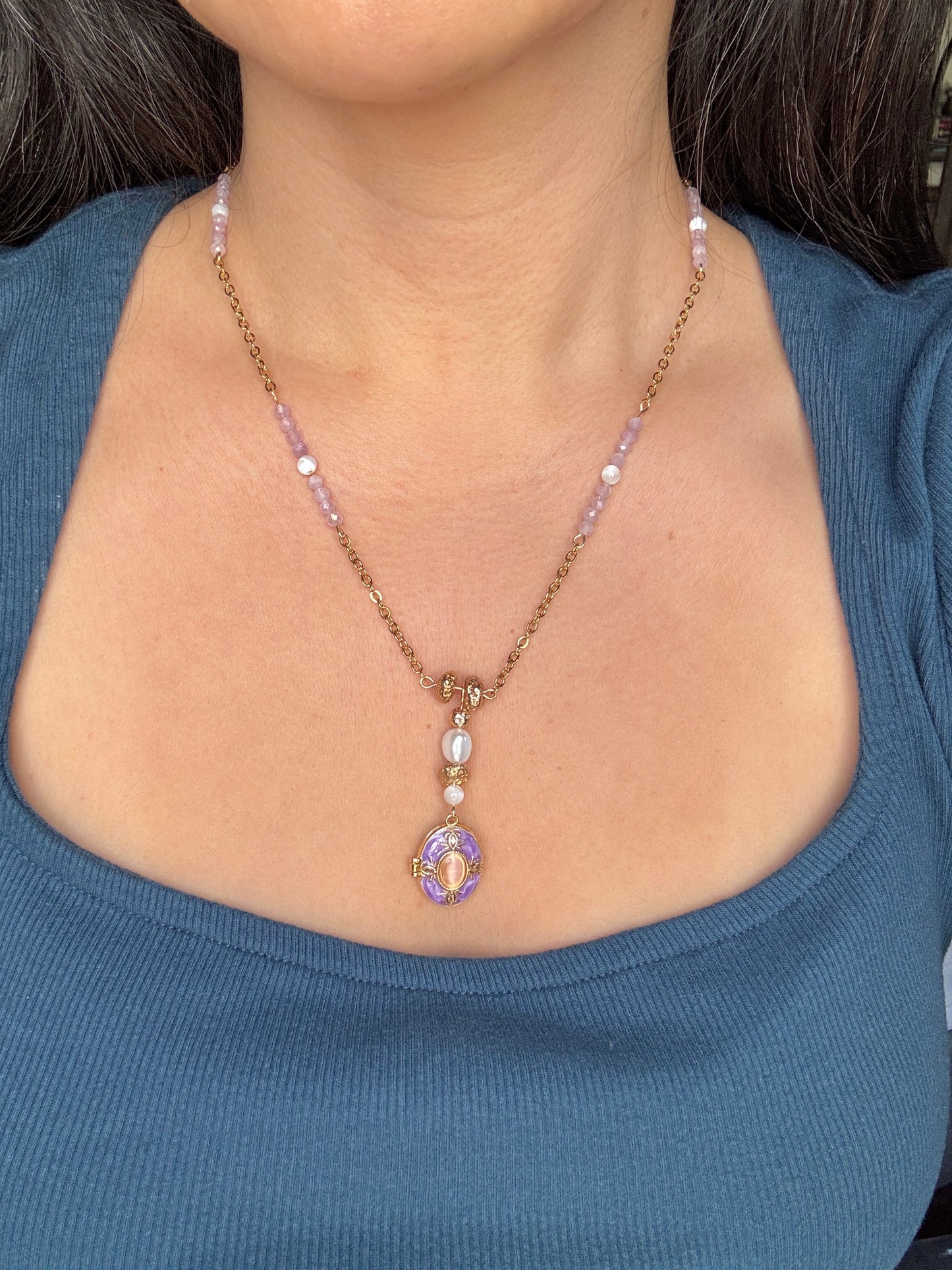 Necklace with a pendant worn by a person in a blue top