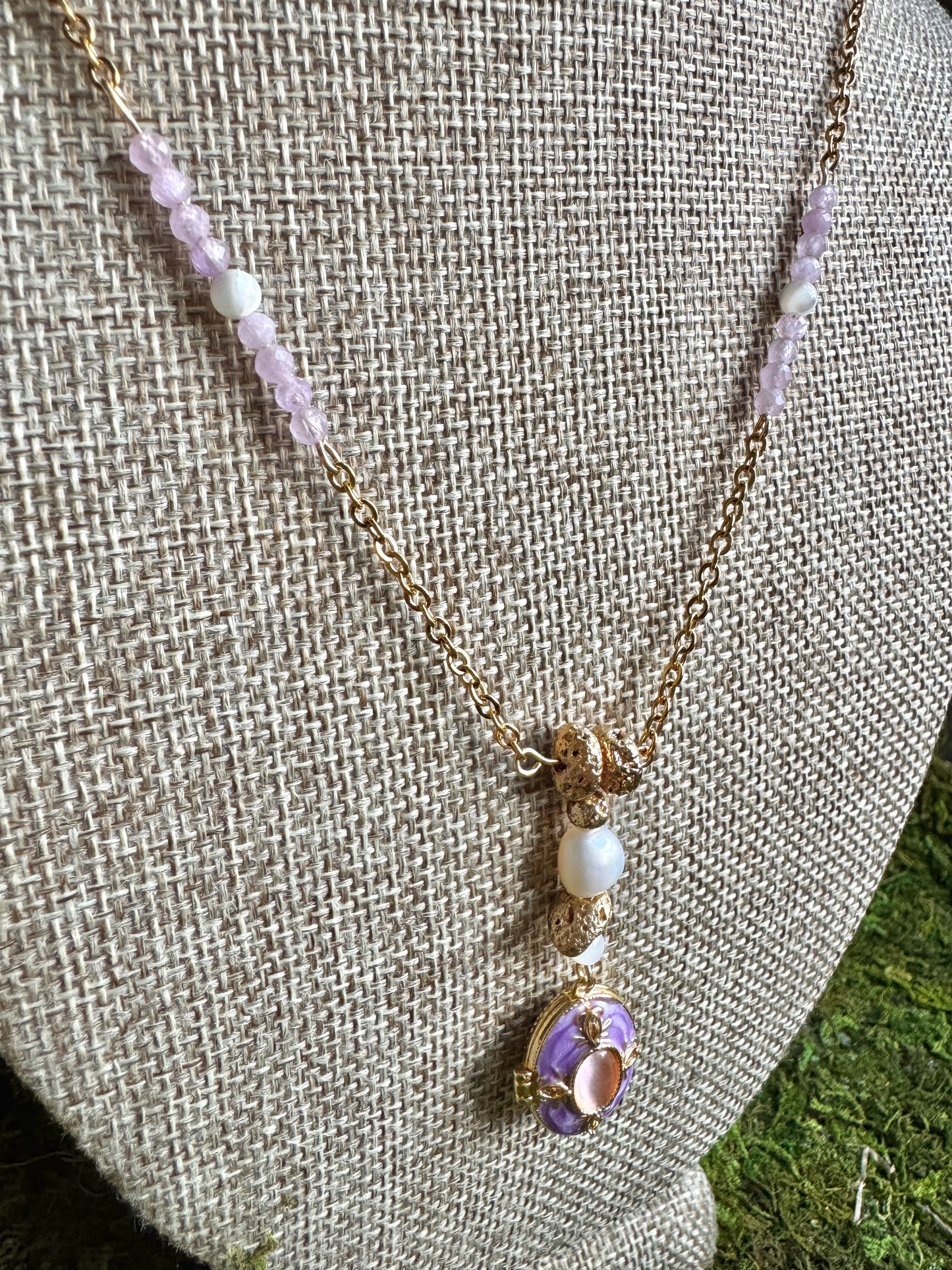 Necklace with purple and gold elements on a gray fabric background
