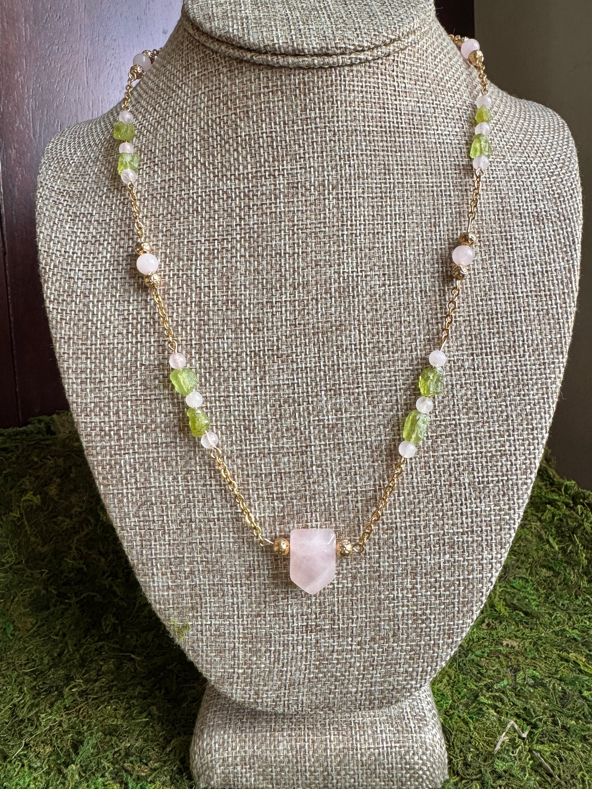 Necklace with green and white beads on a gray bust