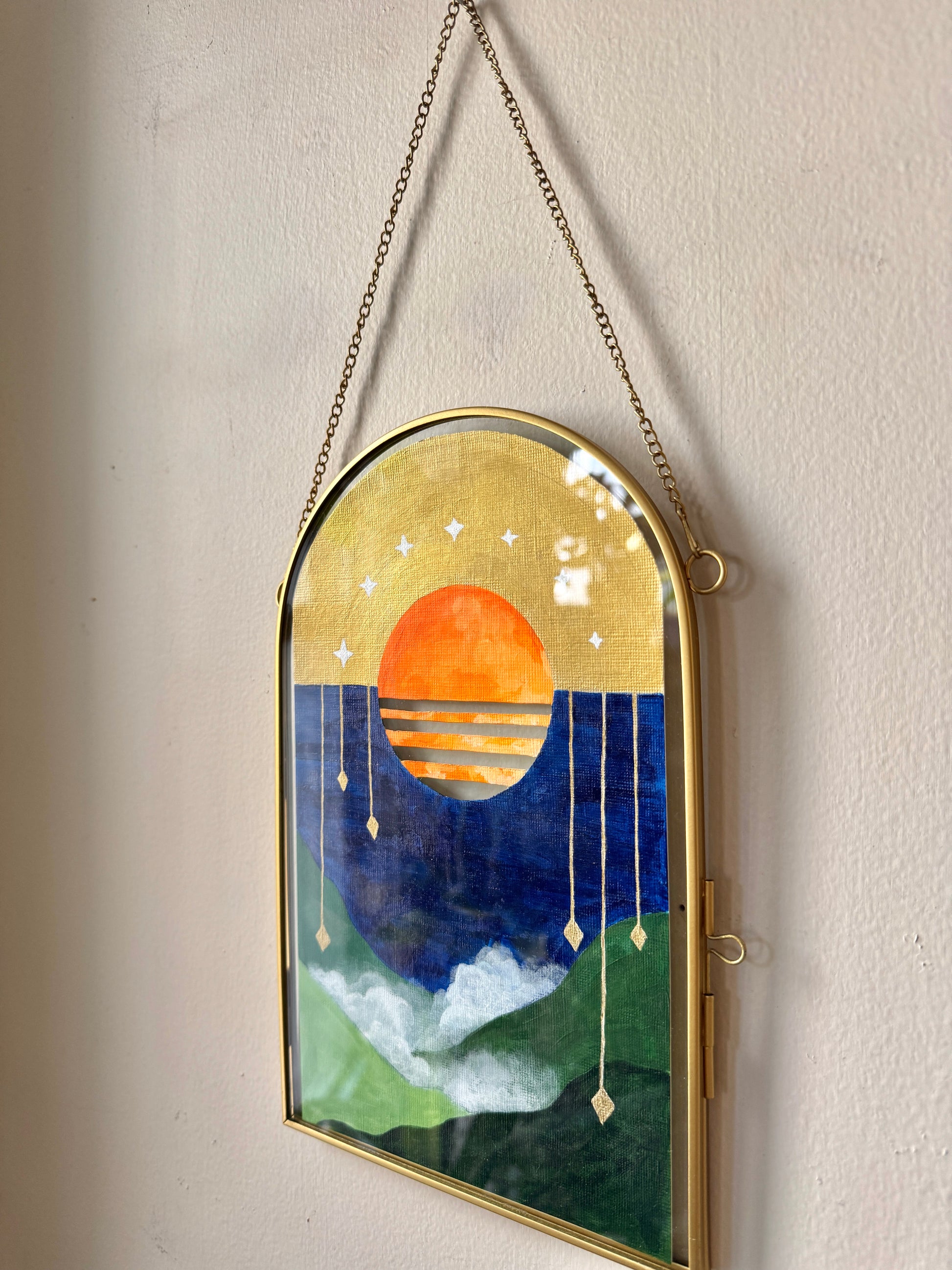 Painting in an arch glass frame hanging on a wall