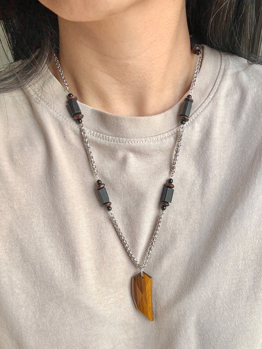 Necklace with a large yellow pendant worn by a person on a plain background