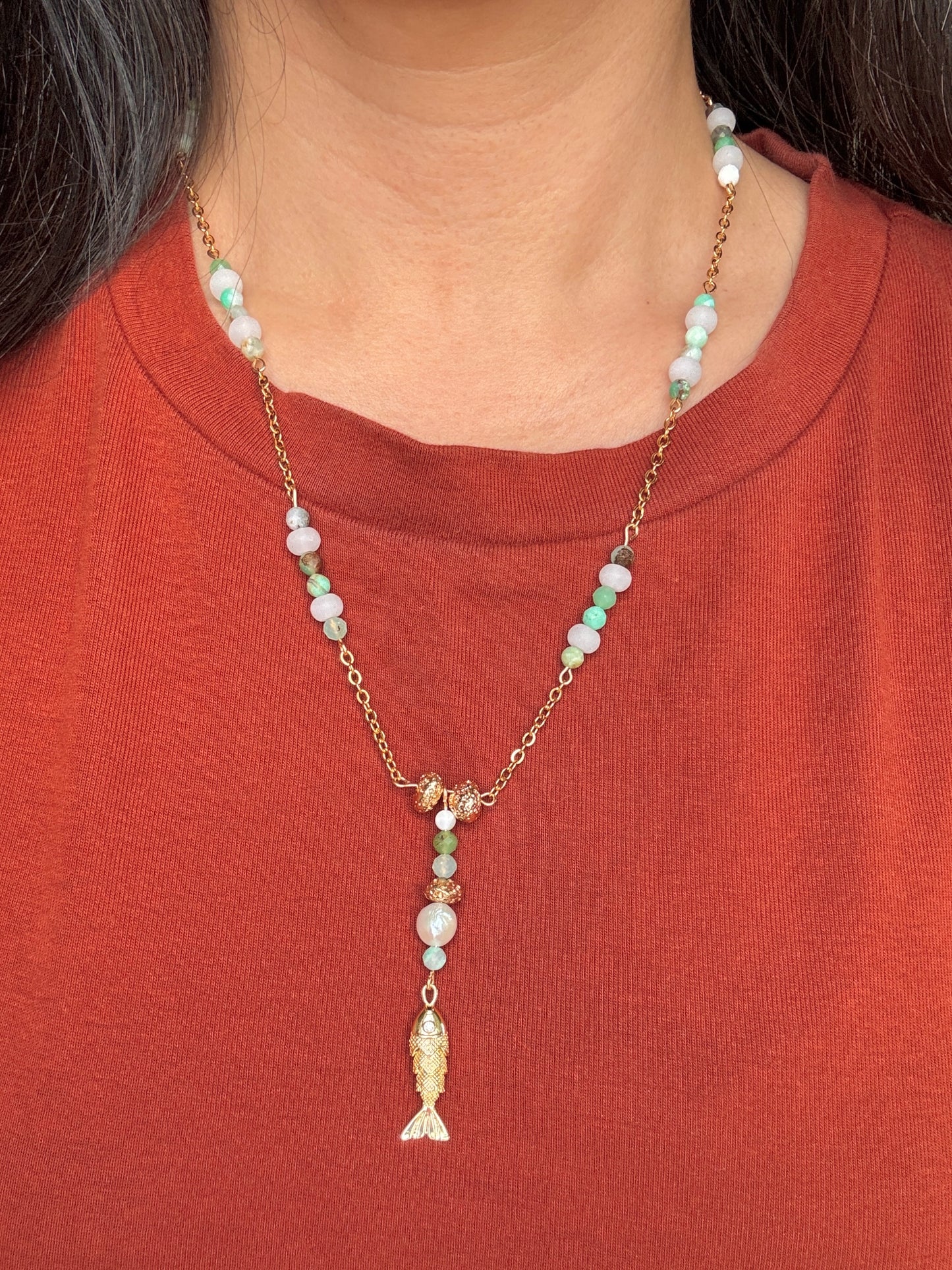 Necklace with fish pendant worn by a person on a red shirt