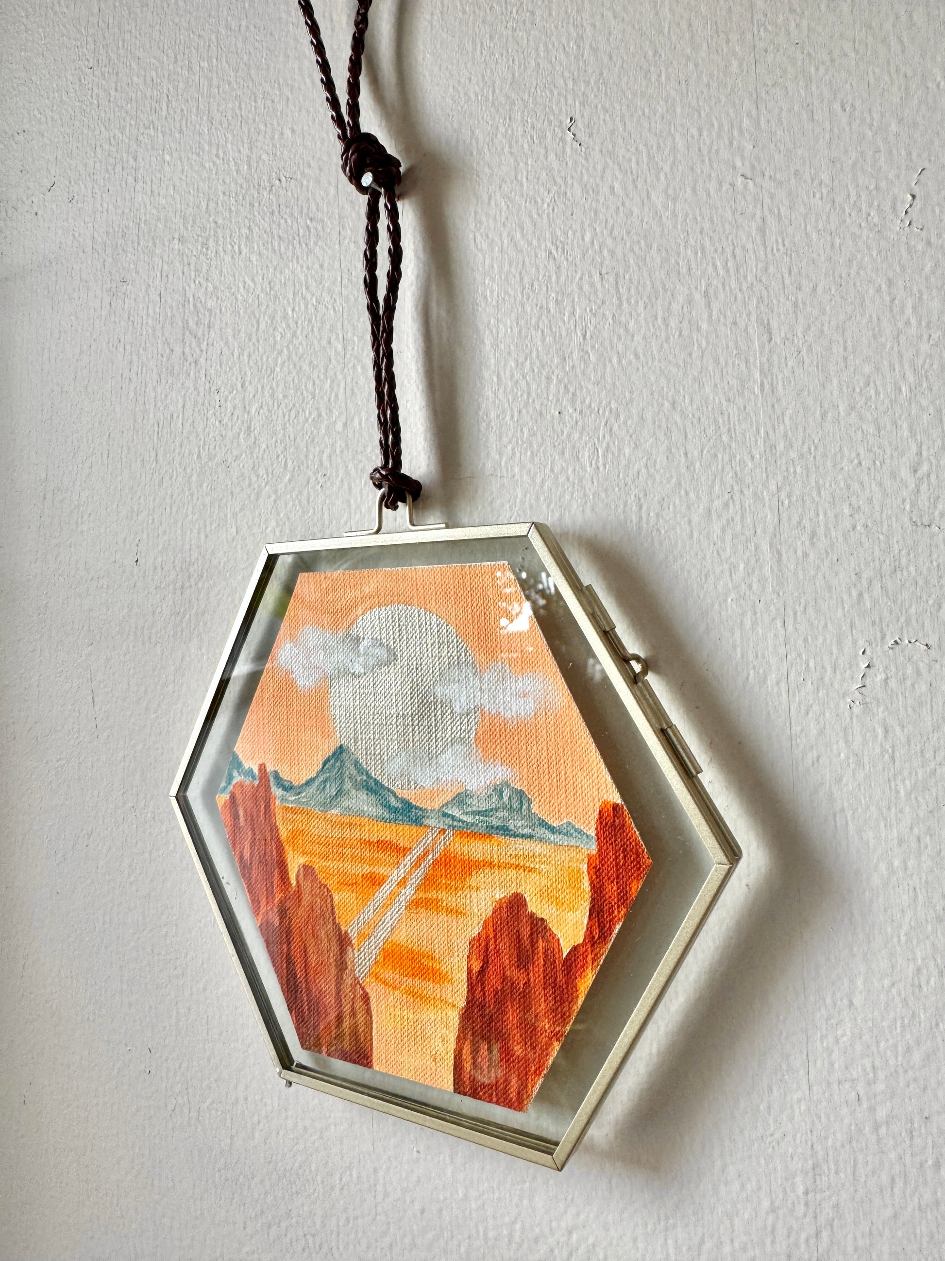 Glass framed landscape painting hanging on a white wall