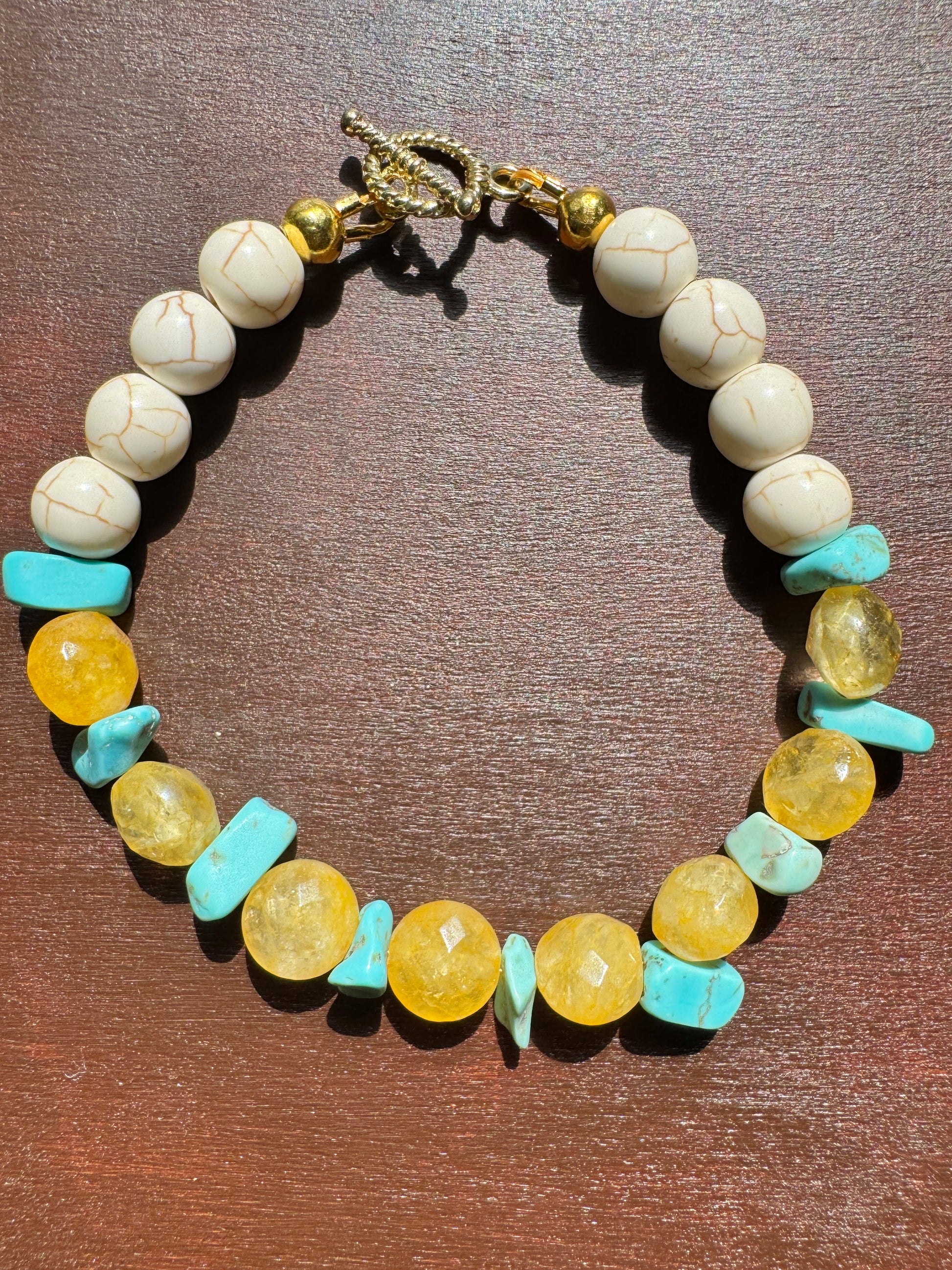 Necklace with white, yellow, and blue beads on a brown surface