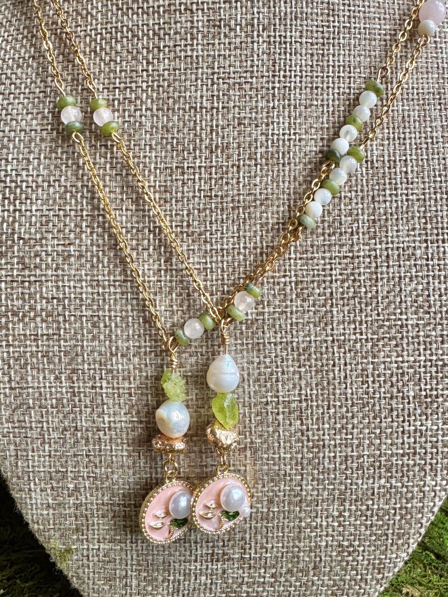 Necklace and earrings with green and white beads on a textured fabric background