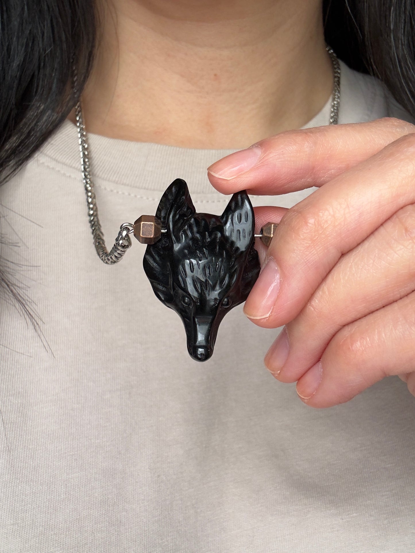 Person holding a black dog-shaped pendant with a chain
