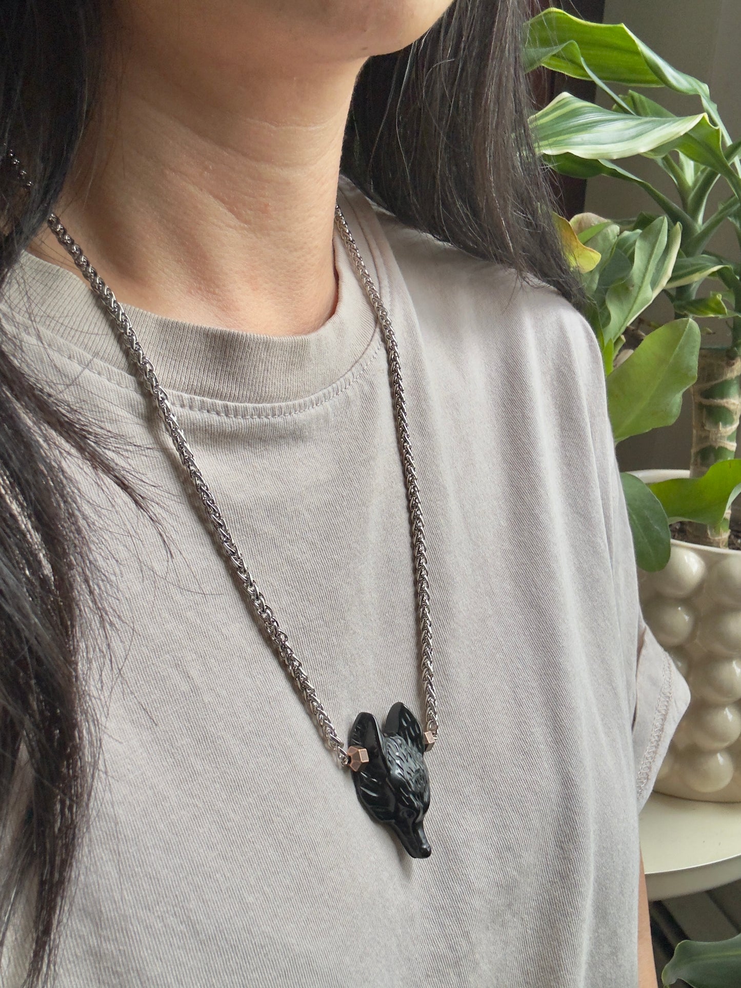 Person wearing a necklace with a wolf pendant in a casual setting
