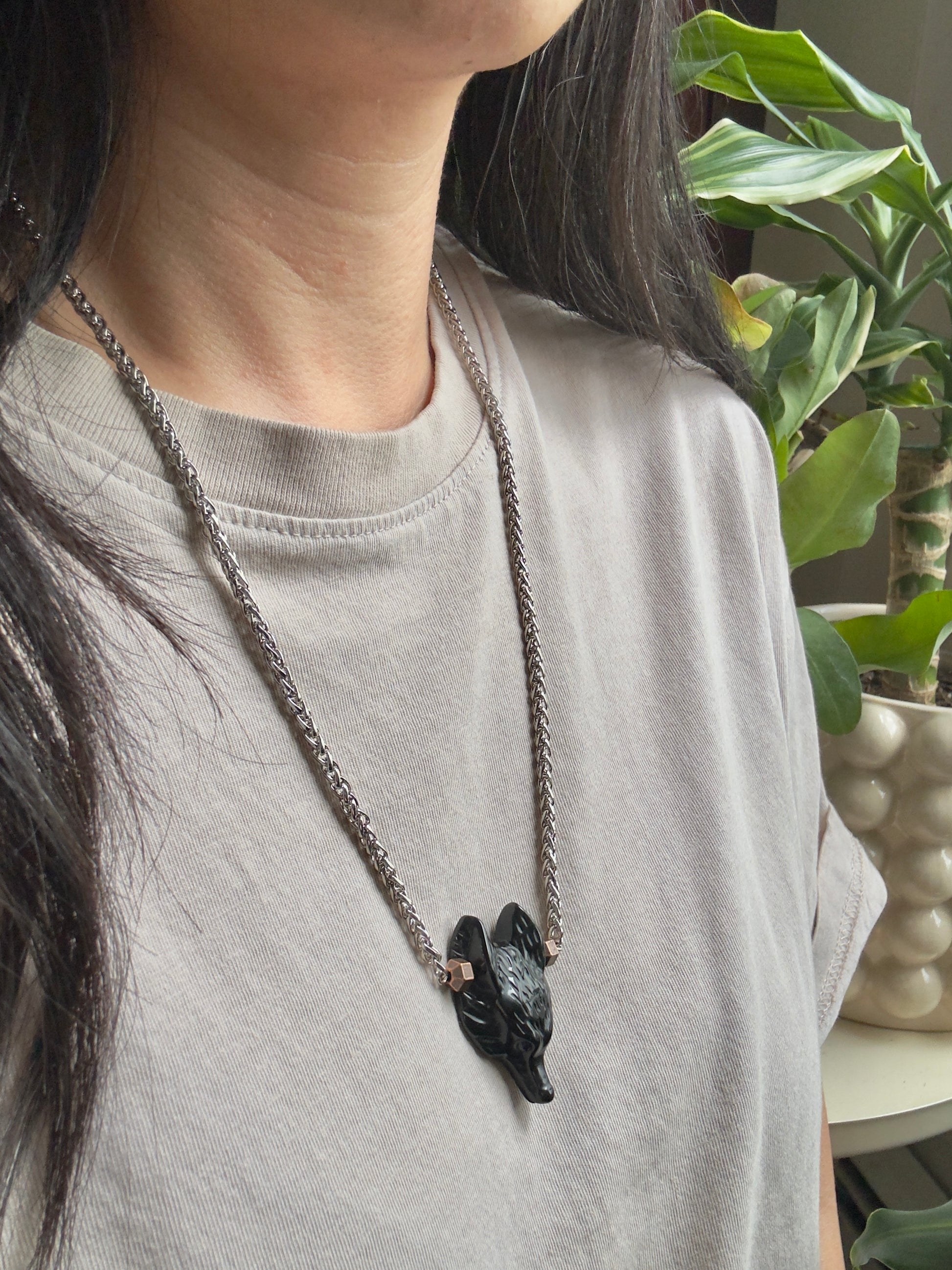 Person wearing a necklace with a wolf pendant in a casual setting